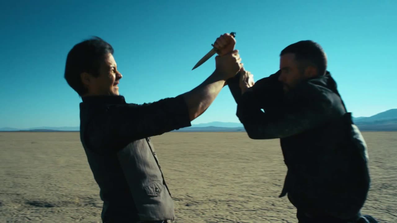 Two men fighting over a knife on a salt flat