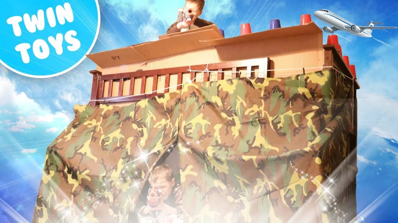 A camouflage box fort under a blue sky with the Twin Toys logo