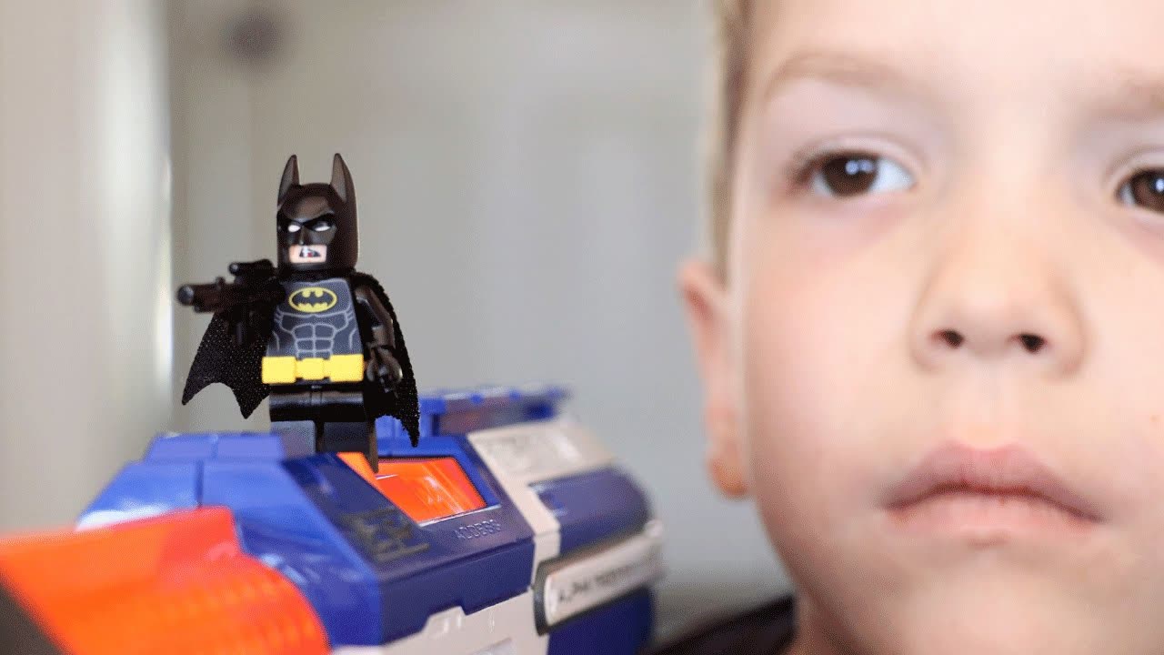 A LEGO Batman figure on a Nerf blaster beside a boy